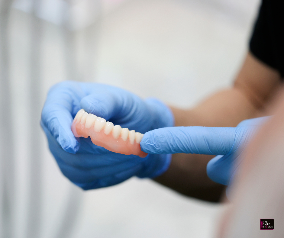 Dentist with gloved hands holding a set of top dentures